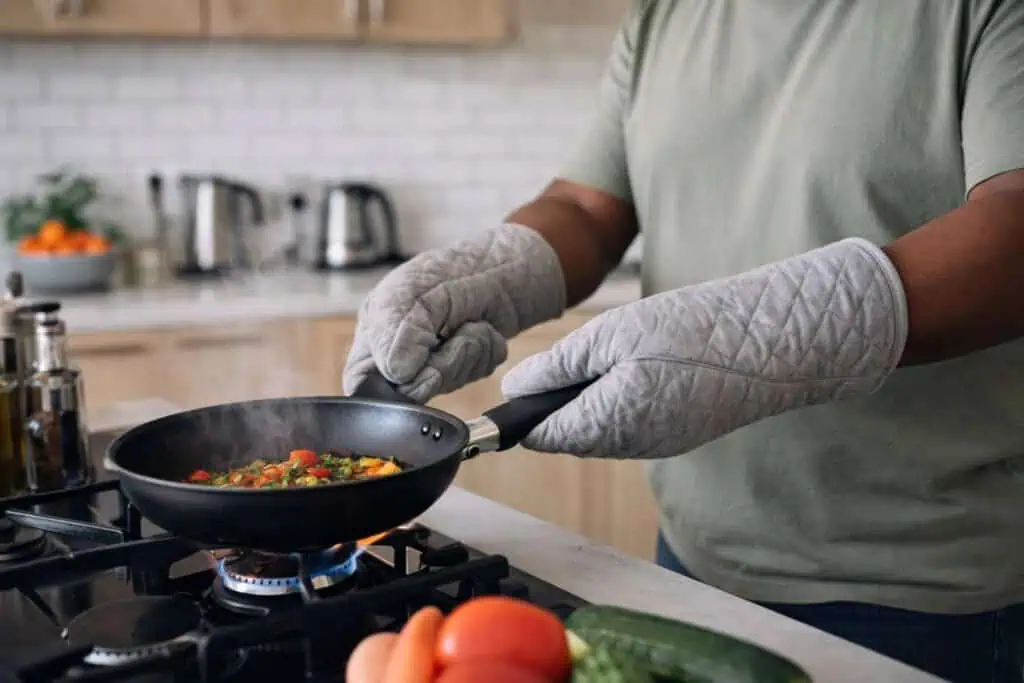 Cook using oven gloves to handle a hot pan safely