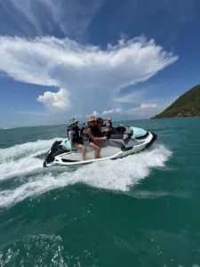 מטיילים דוהרים על אופנוע ים במים כחולים מול הרים ירוקים בקו לאן – איסטקארד