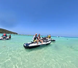 מטייל מחייך על אופנוע ים במים טורקיז צלולים של קו לאן – איסטקארד