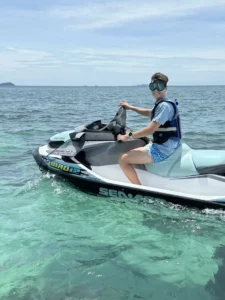 מטייל מחייך על אופנוע ים במים טורקיז צלולים של קו לאן – איסטקארד