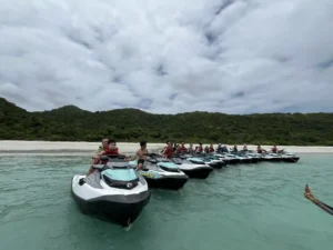 חבורה של מטיילים על אופנועי ים במים רדודים מול חוף לבן בתאילנד – איסטקארד