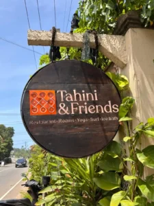 שלט עץ עגול של Tahini and Friends בכניסה למתחם - איסט קארד