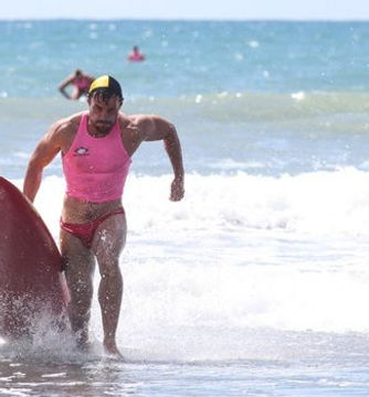 Experienced lifeguard in pink uniform running out of the water at East End Surf Life Saving Club.