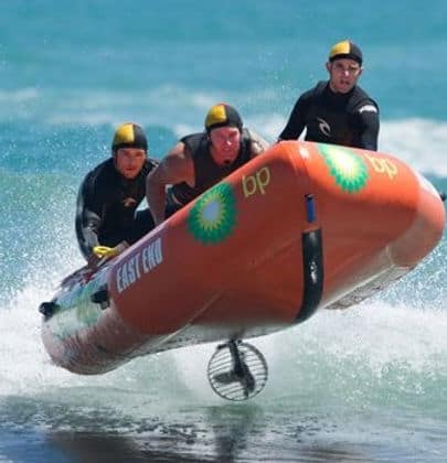 Young surf lifesavers practicing rescues with an inflatable boat at East End Beach, New Zealand.
