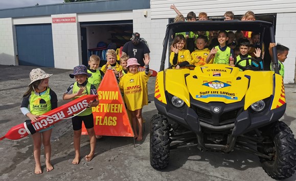 Kids learning surf safety at East End Surf Life Saving Club with flags and rescue equipment.