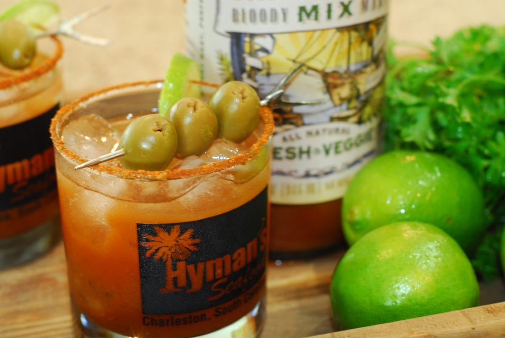 Classic Bloody Mary cocktail garnished with green olives and lime wedge.