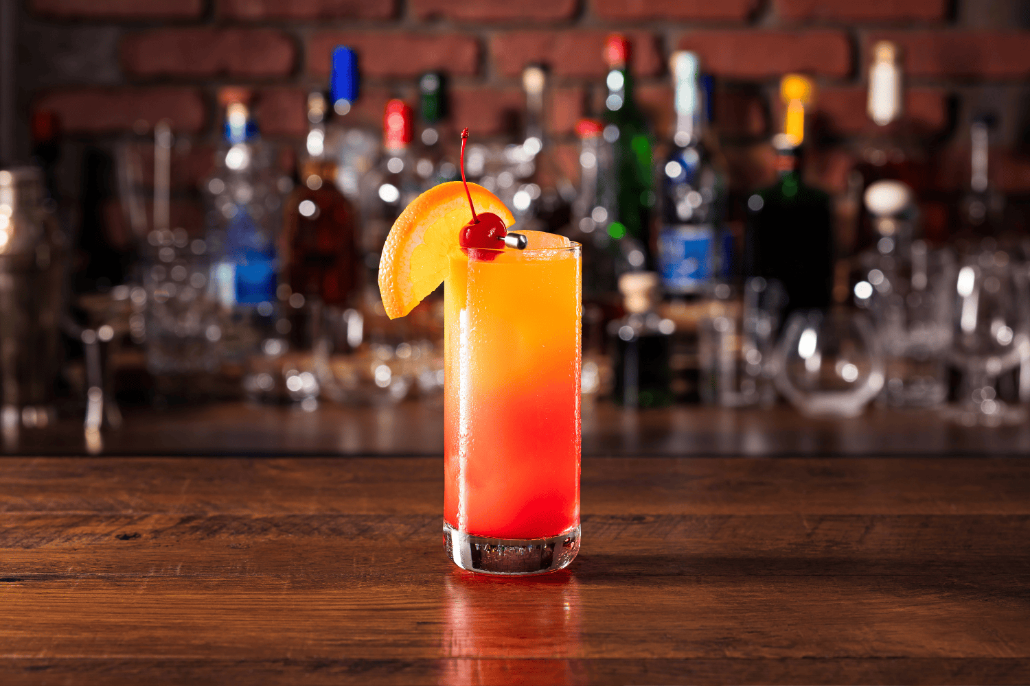 Tequila Sunrise with a slice of orange and a cherry
