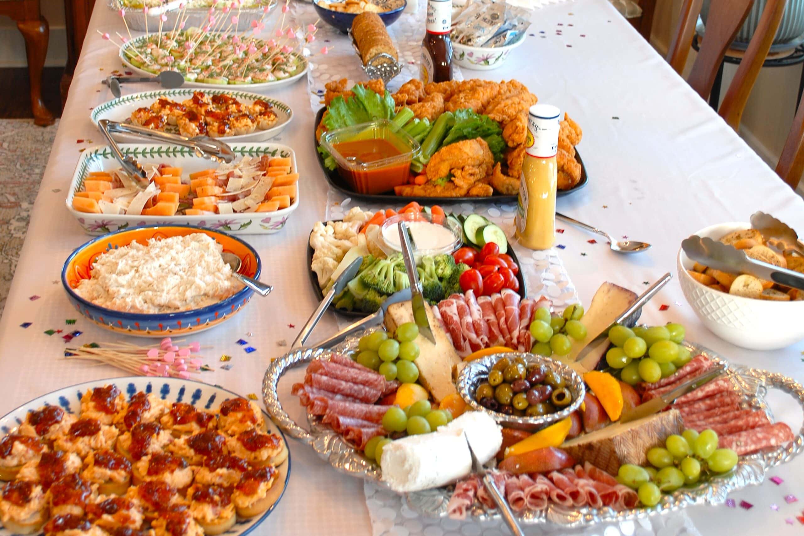 The table features an assortment of cheeses, meats, fruits, and finger foods, ideal for entertaining guests at a casual get-together.