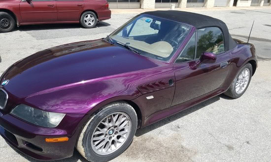 Purple BMW Z3 convertible parked outdoors, showcasing a sleek design and soft top roof.