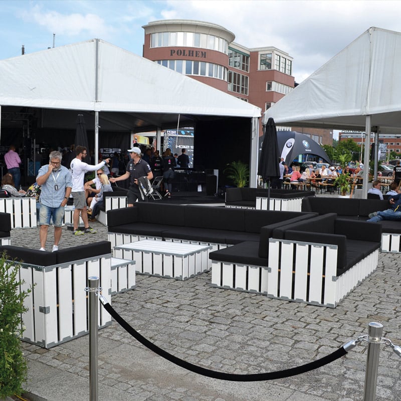 Modern outdoor event seating with black and white furniture at a corporate gathering.