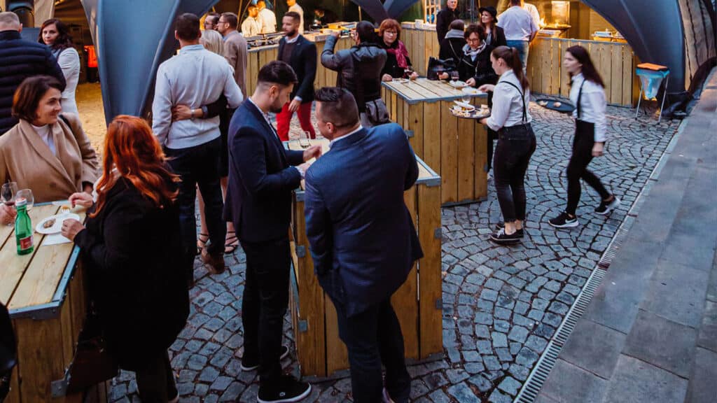 Casual outdoor networking event with people socializing and enjoying food and drinks.