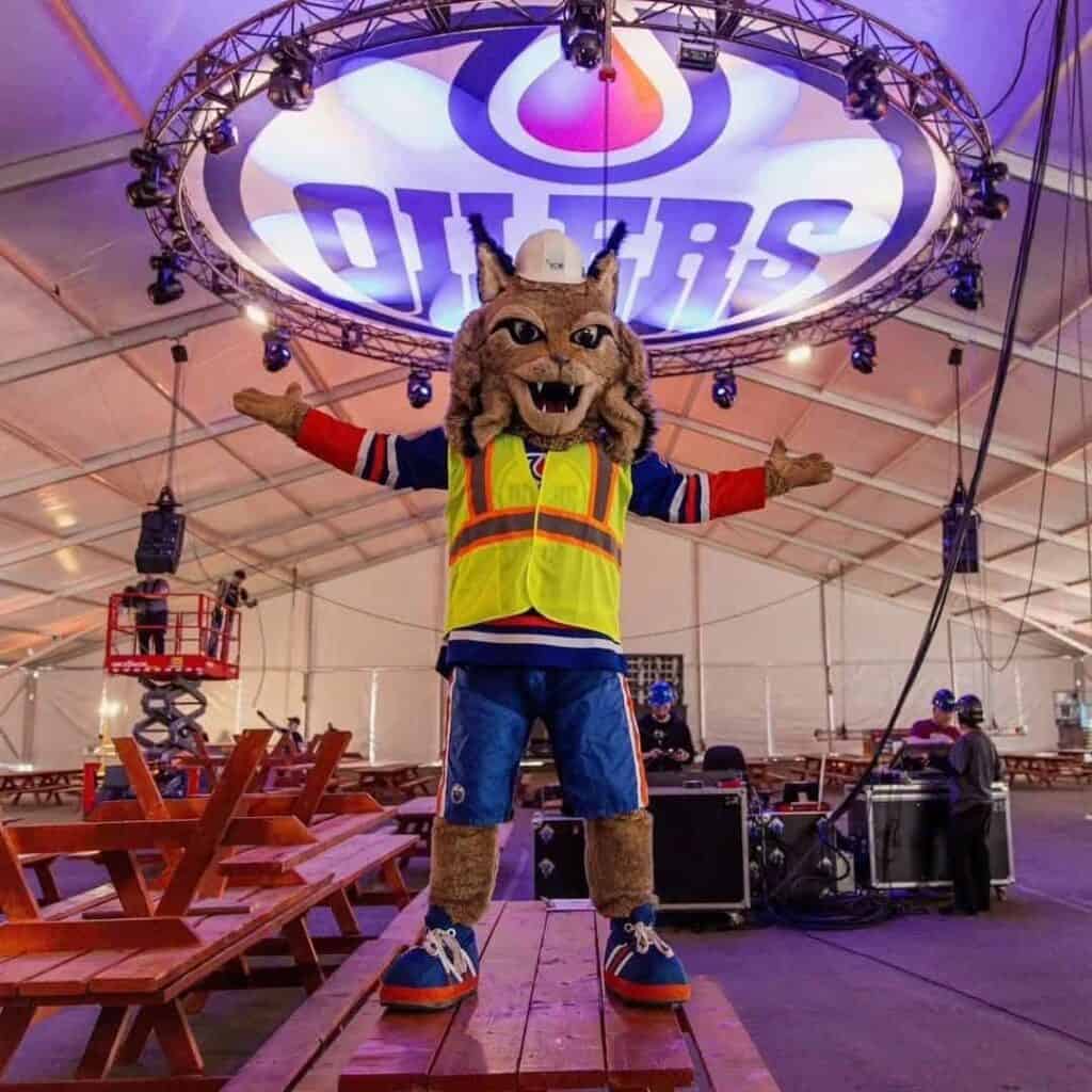 Colorful sports mascot costume of a wildcat wearing a safety vest at EJH Distribution event.