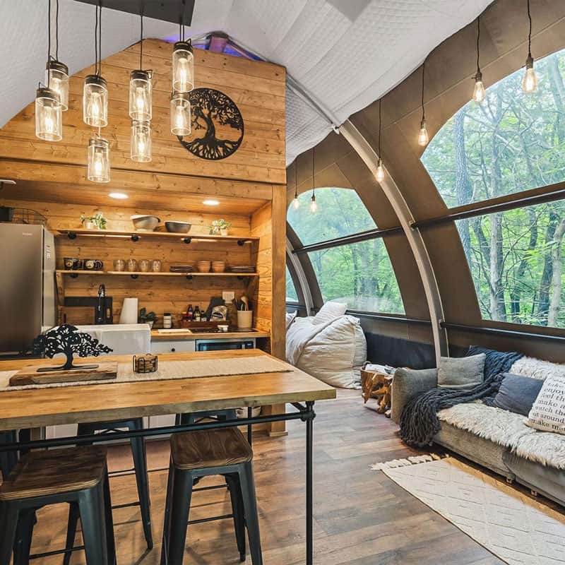 Rustic cozy tiny home interior with wood accents and large forest views for eco-friendly living.
