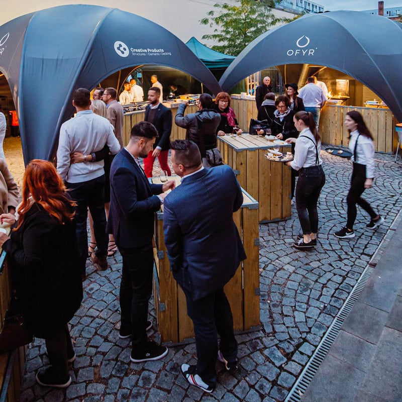 Creative outdoor event with people enjoying food at EJH Distribution's branded tents and modern setup.