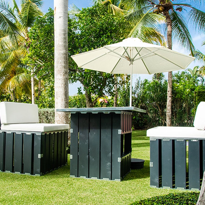 Relaxing outdoor patio furniture set with umbrella on a sunny tropical garden.