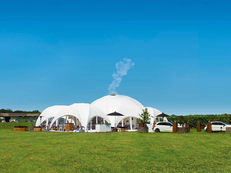 a white dome tent with a car in the background