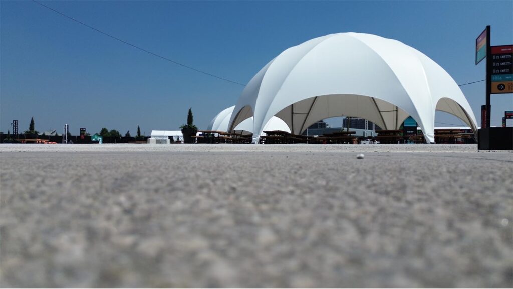 Modern outdoor event tent with white fabric, set up on a paved surface for gatherings, exhibitions, or festivals - ideal for promotional events, trade shows, and outdoor functions.