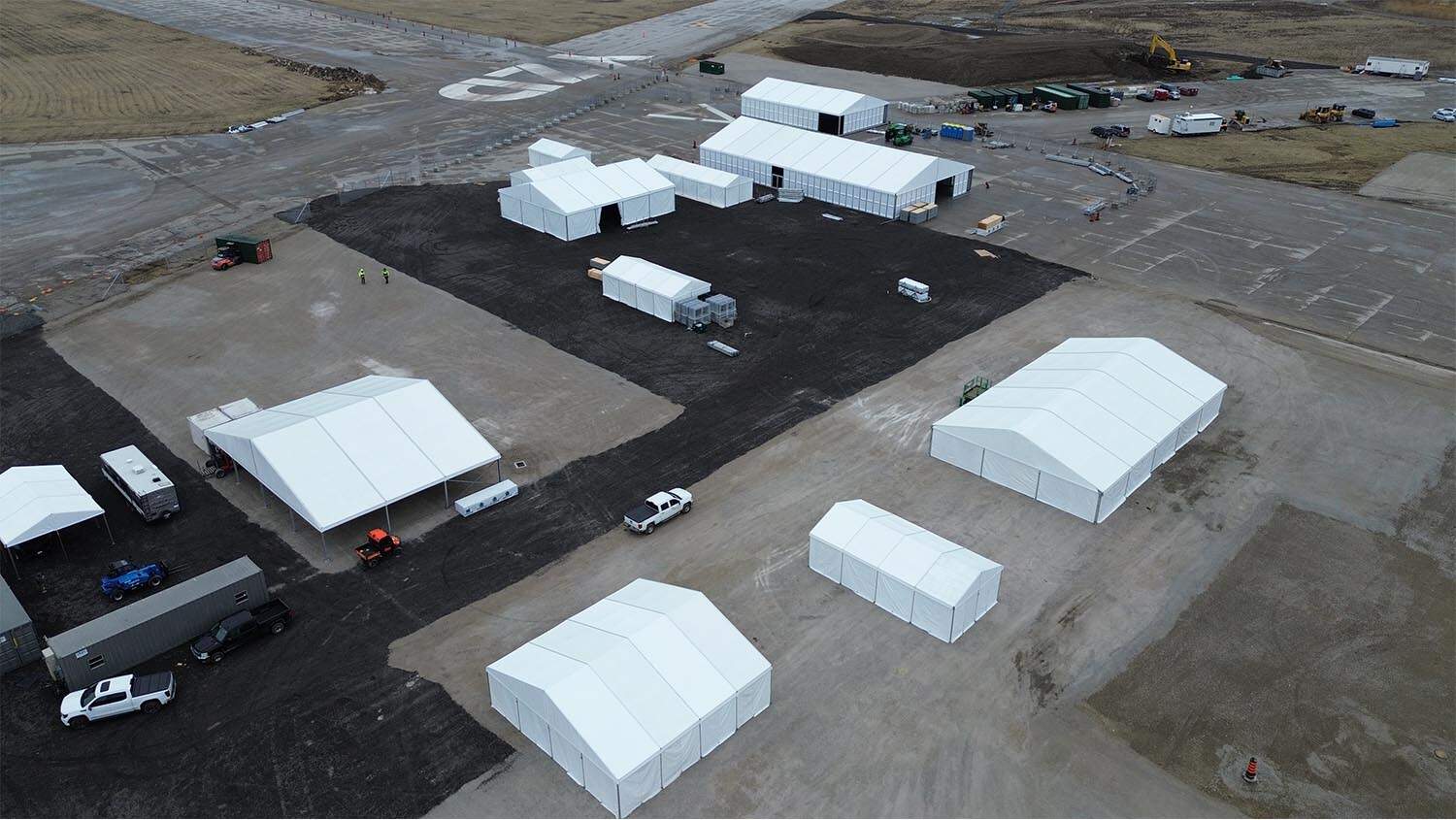 Temporary event tents being set up at a construction site for EJH Distribution facilities. Efficient event tent setup for logistics and distribution operations.