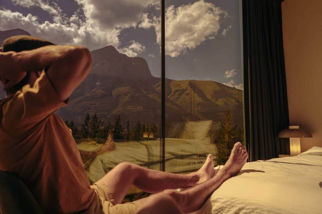 Relaxing hotel room with large glass windows showcasing scenic mountain views and comfortable bedding, perfect for travelers seeking a peaceful retreat.