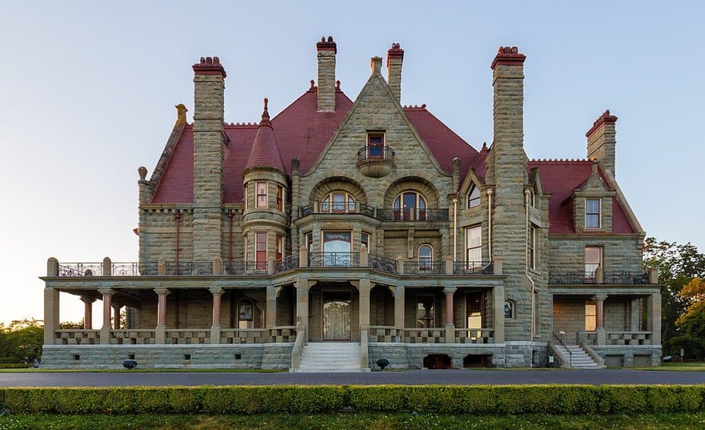 Lavish Victorian mansion with historic stone architecture, turret, and spacious porch, showcasing luxury real estate and classic design elements.