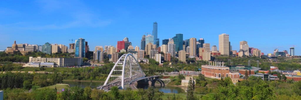 Downtown Austin skyline with modern skyscrapers, the Colorado River, and the Pfluger Bridge under a clear blue sky, showcasing the vibrant city architecture and lush green parks in Texas.