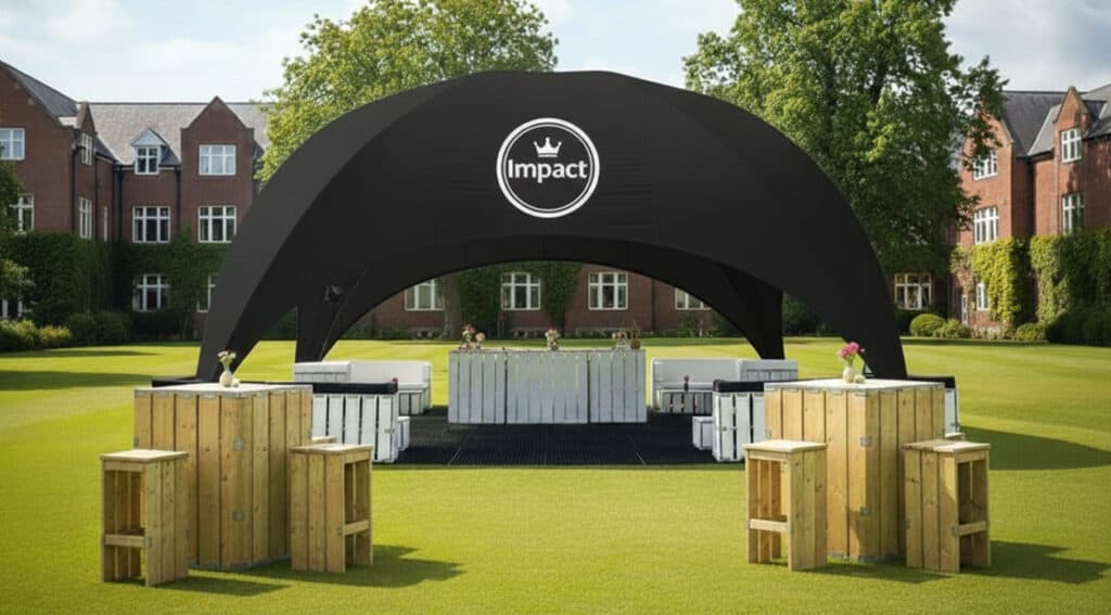 Impact event tent in outdoor open space with a black canopy and white furniture, perfect for outdoor events, parties, and gatherings in lush green surroundings.