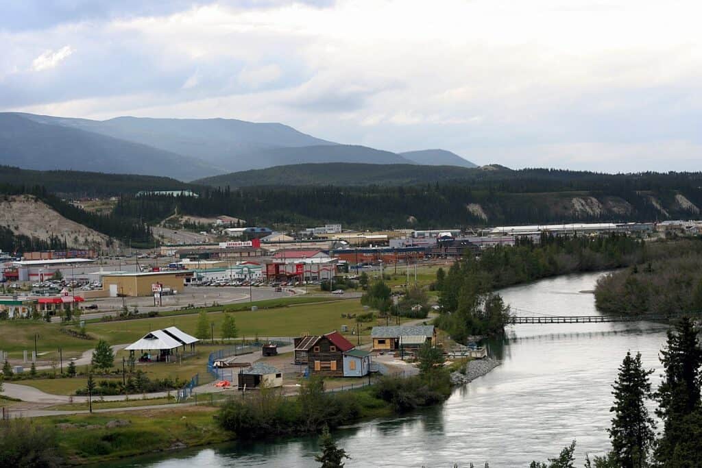 Modern logistics warehouse and distribution center near a river with scenic mountain views, representing EJH Distribution's supply chain and warehousing services.