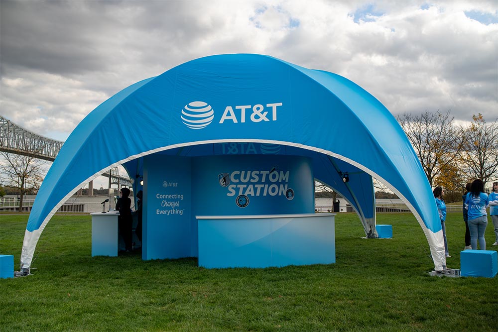 A large blue AT&T branded outdoor event tent serving as a custom station for product demos and customer engagement during an outdoor event.