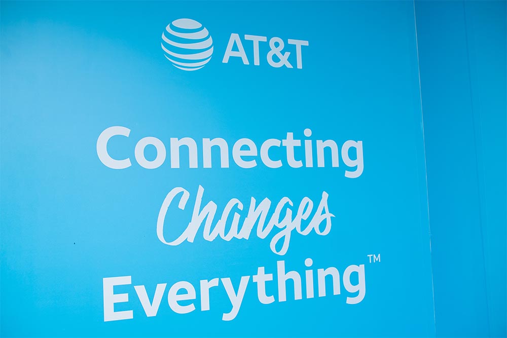AT&T logo with a blue wall background, emphasizing connectivity and innovation in telecommunications industry.
