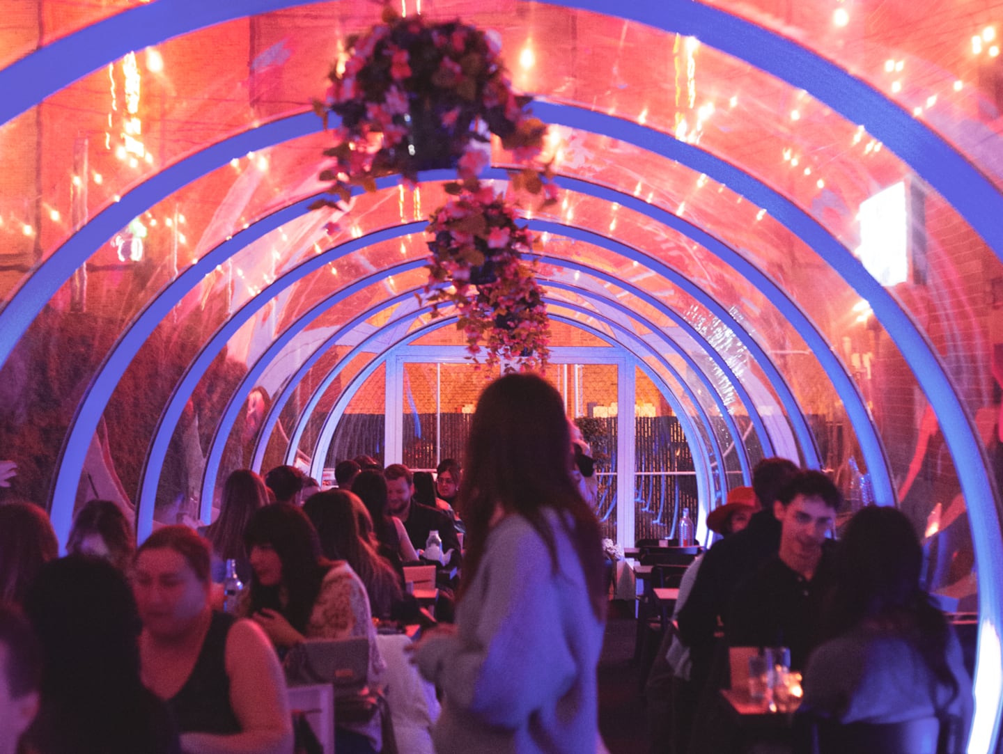 Outdoor patio with vibrant lighting and floral decor at Baijiu, Canada's top restaurant. Perfect for social gatherings, dining, and enjoying a lively atmosphere.