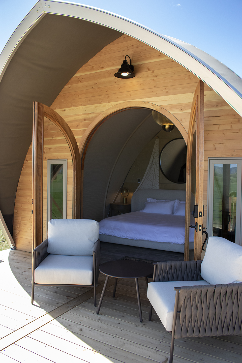 Charming tiny cabin featuring a modern interior with a cozy bedroom, wooden accents, and outdoor seating area. Perfect for a relaxing getaway in nature.