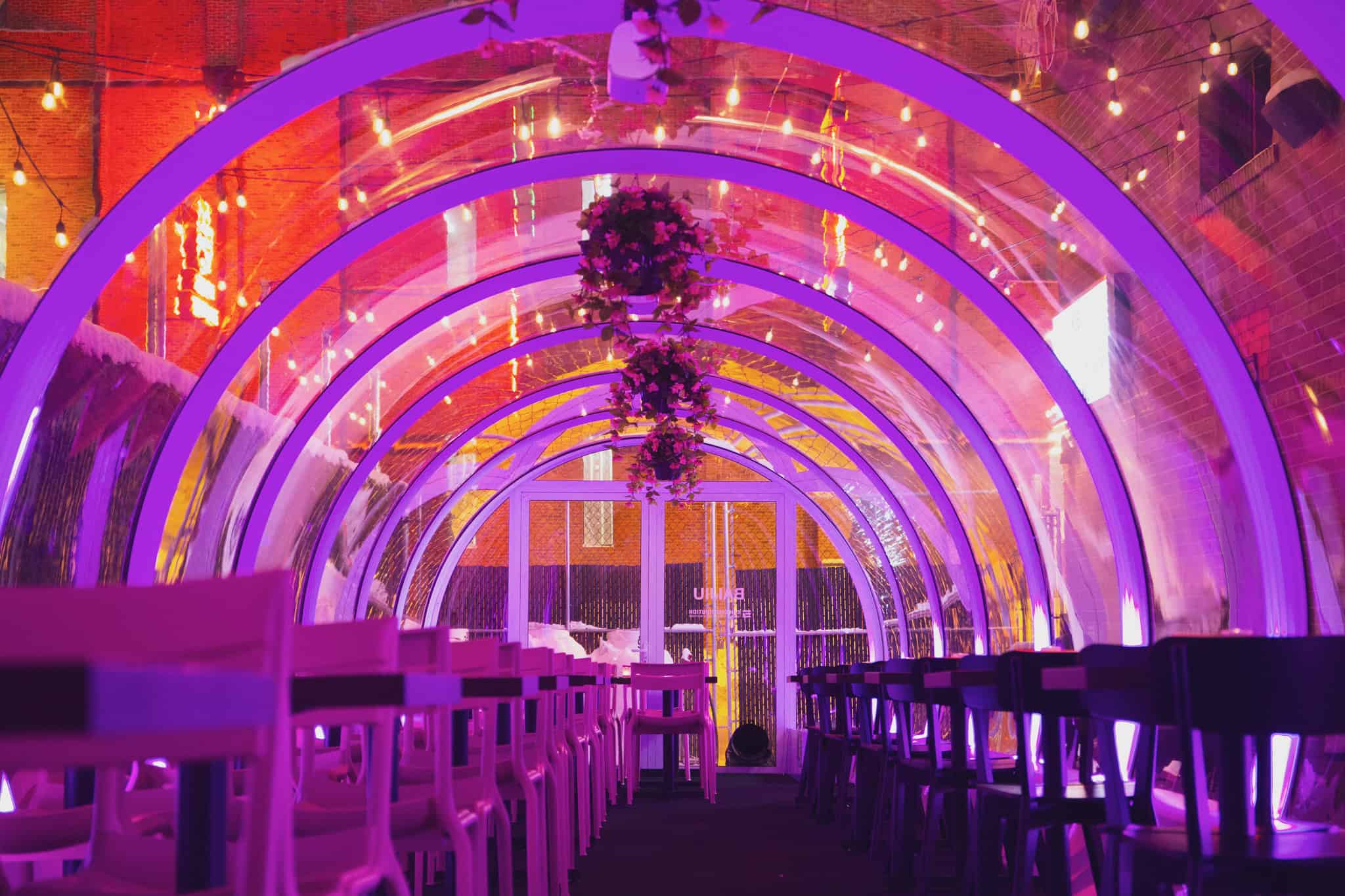 Brightly lit patio featuring colorful neon lights and modern decor, perfect for outdoor dining and social gatherings in Canada.