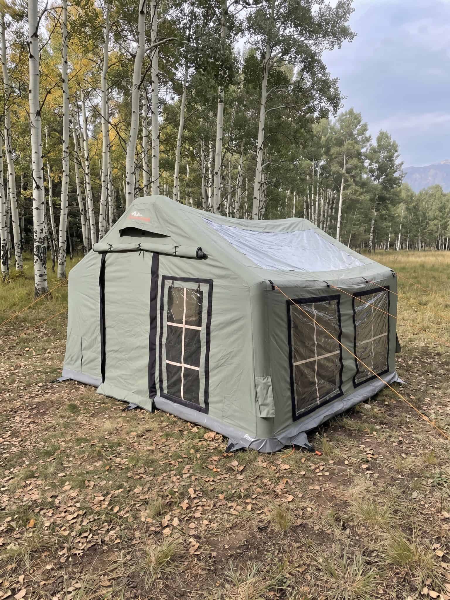 green inflatable tent set up in a field of Aspen trees