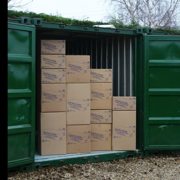 Stacked cardboard boxes inside a green storage container for self storage solutions.