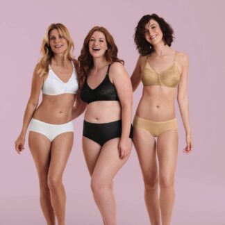 Three women wearing white, black, and beige lingerie stand together and smile against a pink background.