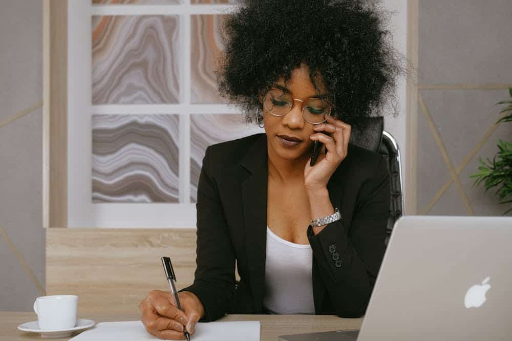 Mulher, usando blusa preta, conversando ao telefone. Ilustração do texto sobre franquias 2020 tendências.