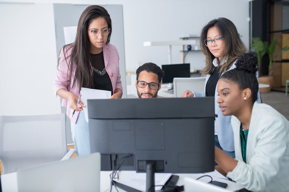 Pessoas atentas analisando computador preto. Ilustração do texto sobre vantagens e desvantagens da franquia para franqueadores e franqueados.