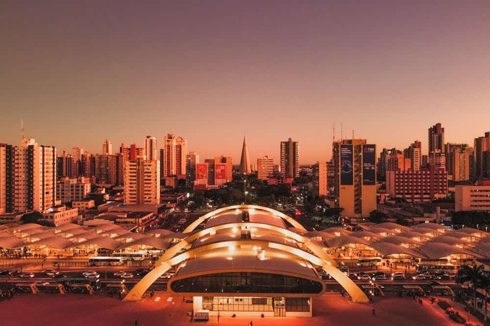 Vista aérea da cidade de Maringá. Podemos observar um pôr-do-sol com iluminação laranja. Ilustração do texto sobre franquia em Maringá;