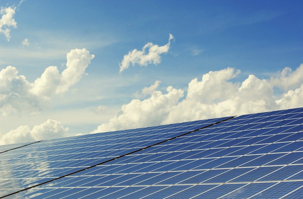 Foto de uma placa utilizada para a obtenção de energia solar. Ao fundo vemos um céu azul com nuvens. Imagem ilustrativa para texto Solarprime diminuição de custos.