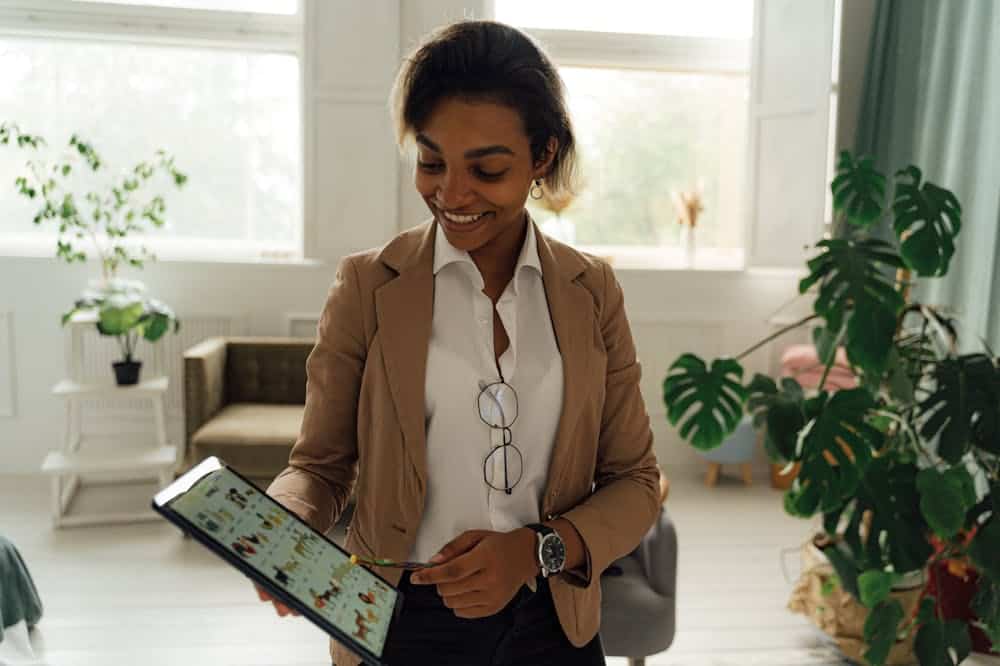 Mulher sorridente, usando blazer marrom, analisando dados. Ilustração do texto sobre franquias sem custo.