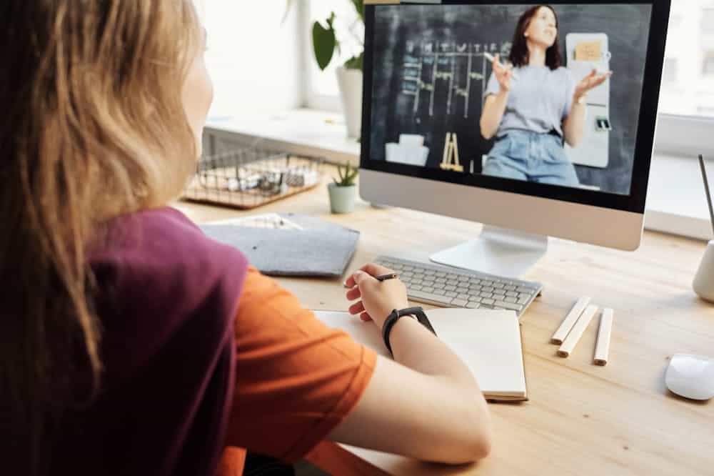 As franquias mais lucrativas em 2022 e que vão se manter crescendo Mulher usando blusa laranja, observando a tela do notebook. Ilustração do texto sobre franquia Home Office StartupWin.
