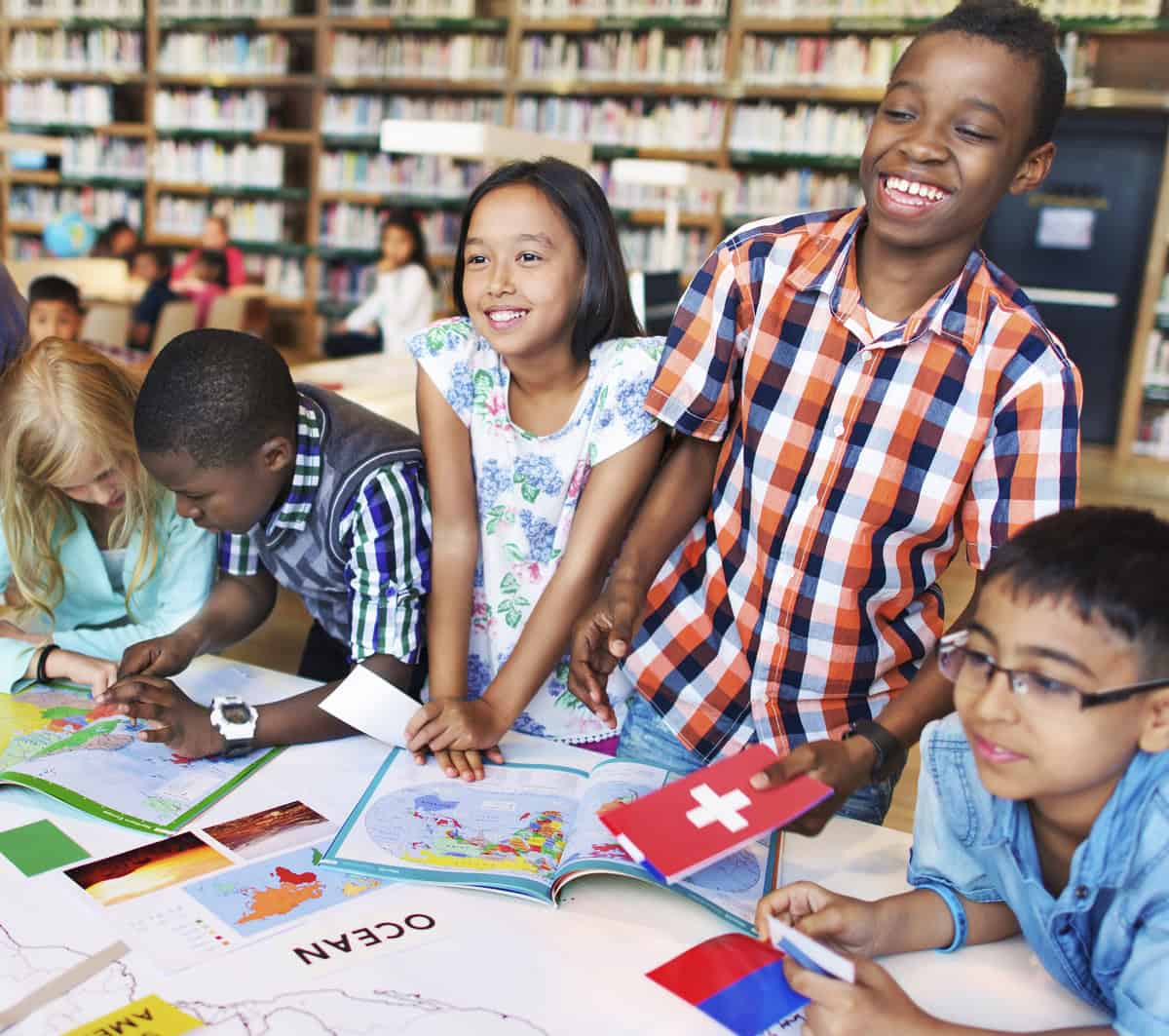 Crianças analisando mapa em biblioteca. Ilustração do texto sobre franquia de educação fundamental.
