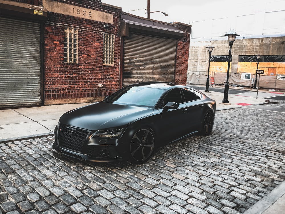 Carro preto em uma rua deserta com lojas fechadas. 
