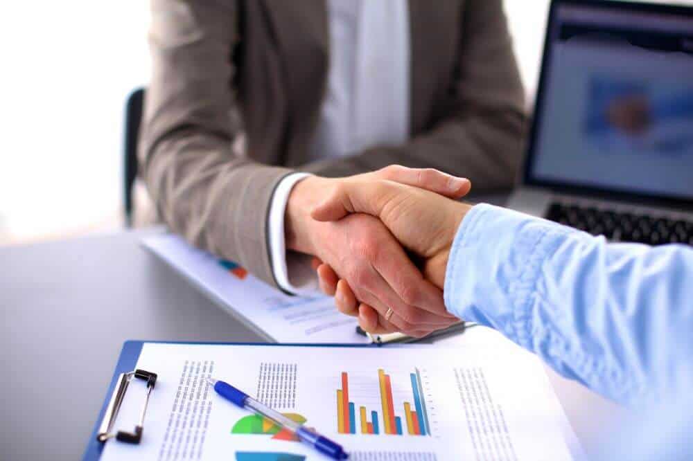 Licenciamento ou Franquia? 15 modelos de negócio famosos 2026 pessoas apertando as mãos. Imagem ilustrativa do texto sobre franchising e licenciamento