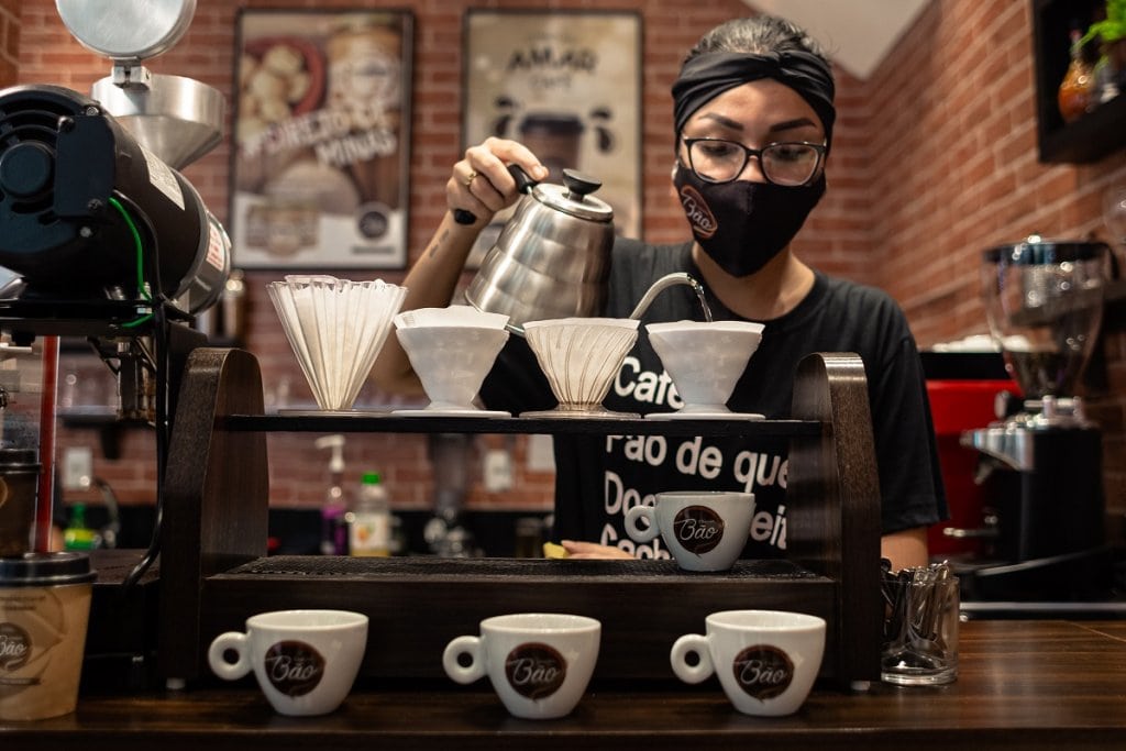 Barista usando máscara preparando cafés na franquia Cheirin Bão.