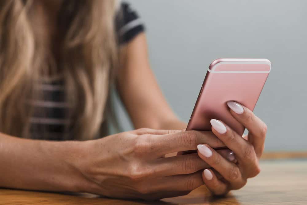 mulher mexe em um celular rosa. Imagem ilustrativa do texto sobre franquia Keep Charged