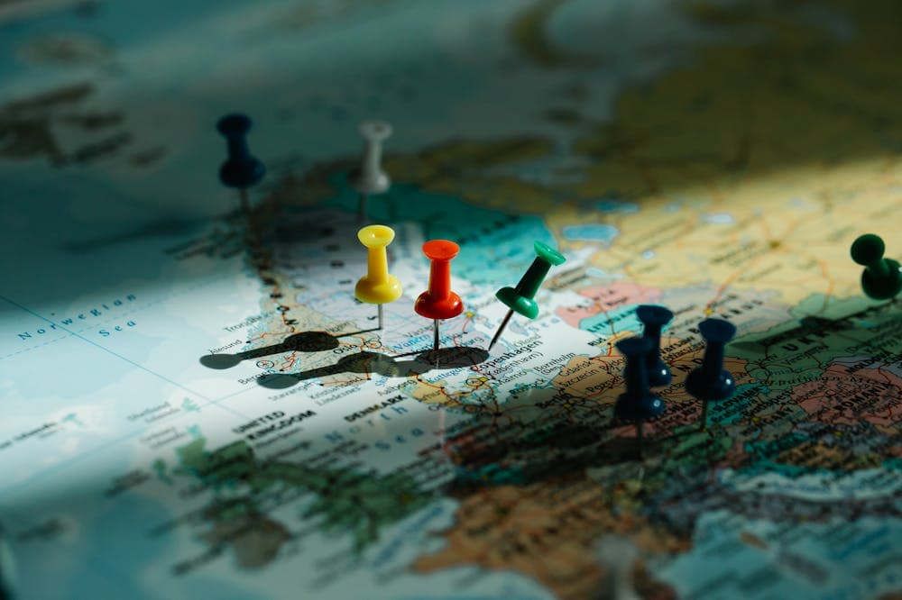 Mapa mundi com pinos inseridos na cor amarela, vermelha e mais. Ilustração do texto sobre ideias de negócios que deram certo no exterior.