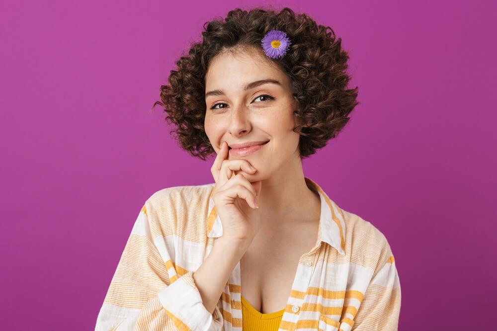 mulher sorrindo com mão na boca em fundo rosa. Imagem ilustrativa do texto sobre franquias baratas 2023.