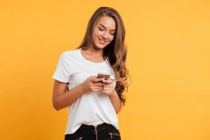 mulher sorrindo mexendo em celular. Imagem ilustrativa do texto sobre franquias lucrativas 2023