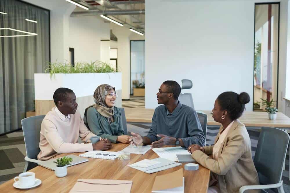 Pessoas sentadas em torno de uma mesa de madeira marrom. Ilustração do texto sobre nichos promissores.